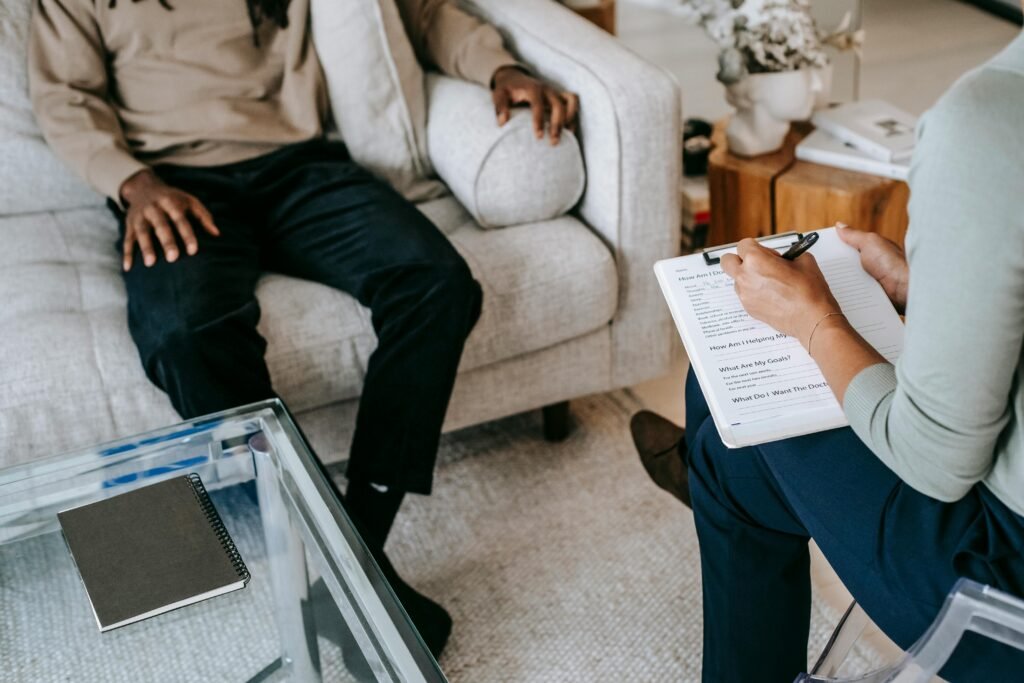 pexels-photo-5699466-5699466 From above crop African American male in casual clothes sitting on comfy couch and answering professional female consultant questions in modern psychotherapy office